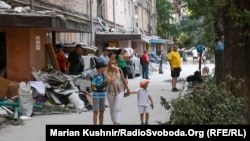 Люди чекають завершення пошуково-рятувальних робіт біля зруйнованого будинку