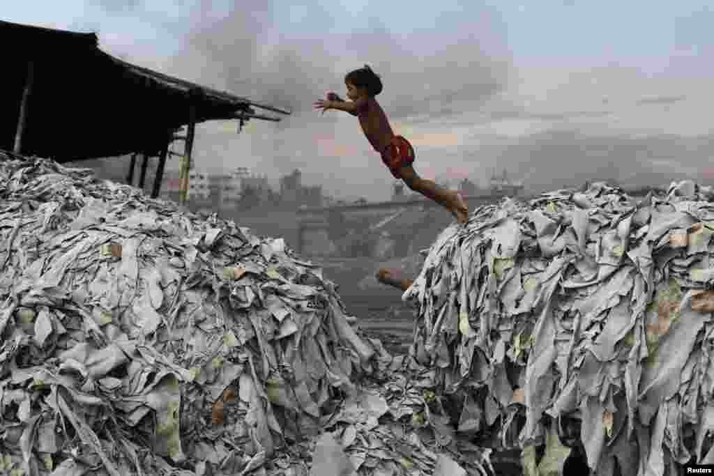 A Bangladeshi boy jumps on waste products that are used to make poultry feed as she plays in a tannery in Dhaka.