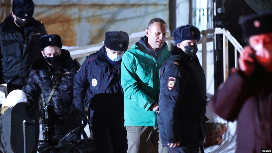 Kremlin critic Aleksei Navalny (in green jacket) is escorted by police officers after a court hearing in Khimki outside Moscow on January 18. 
