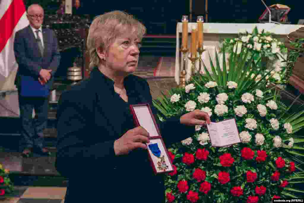 Іна Кулей трымае Афіцэрскі крыж «За заслугі» Рэспублікі Польшча, якім польскі прэзыдэнт Караль Наўроцкі пасьмяротна ўзнагародзіў Аляксандра Мілінкевіча