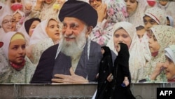  Iranian women walk past a banner bearing a portrait of Iran's supreme leader, Ayatollah Ali Khamenei, on February 22. 