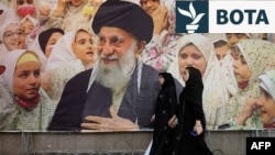 Dy gra iraniane duke ecur mbrapa portretit të liderit suprem, Ajatollah Ali Khamenei në Xhaminë e Madhe të Teheranit, më 22 shkurt 2026.