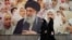  Iranian women walk past a banner bearing a portrait of Iran's supreme leader, Ayatollah Ali Khamenei, on February 22. 