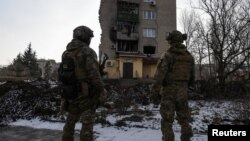 Українські військові біля зруйнованої російським обстрілом будівлі, 17 січня 2023 року