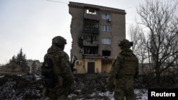 Ukrainian servicemen stand next to a residential building heavily damaged by a Russian military strike in Bakhmut. 