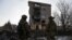 Ukrainian servicemen stand next to a residential building heavily damaged by a Russian military strike in Bakhmut. 