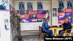 Georgian men play dominoes at a bus stop pasted over with presidential campaign posters in Telavi earlier this week. 