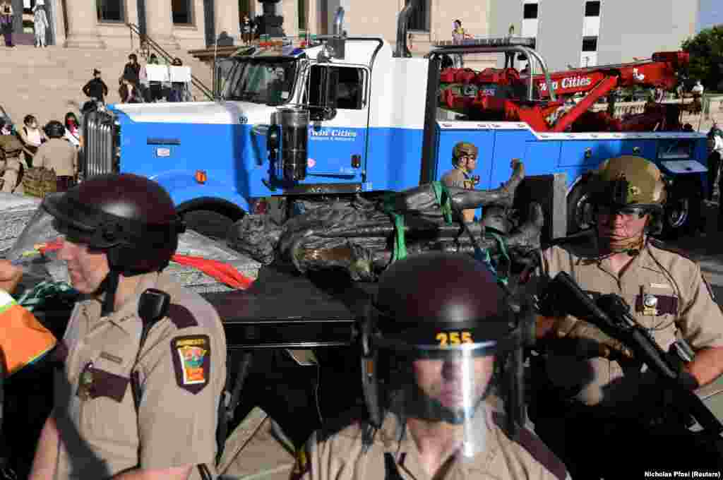Поліція штату Міннесота охороняє працівників, які прибирають скинений демонстрантами пам&rsquo;ятник Христофорові Колумбу, місто Сент-Пол, 10 червня 2020 року.