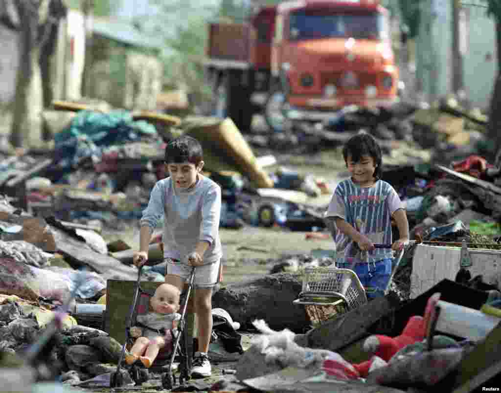 Luciano Montero (left) and Samuel Nunez play among piles of rubbish heaped outside homes in the city of Santa Fe, 480 kilometers north of Buenos Aires, Argentina.