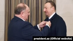 Gennady Zyuganov Kommunist Partiyasının xatirə ordenini Azərbaycan prezidentinin yaxasına taxarkən, Bakı, 9 fevral 2015