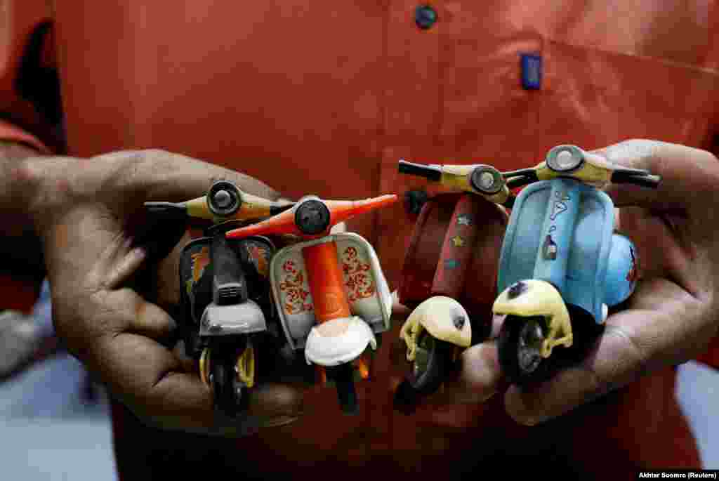 A shopkeeper and Vespa enthusiast holds his collection of mini Vespas at his auto-parts shop in Karachi.&nbsp;