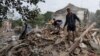 Local residents search for the documents of their injured friend in the debris of a destroyed apartment house after Russian shelling in a residential area in Chuhuiv, near Kharkiv, on July 16.