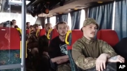 In video released by the Russian Defense Ministry on May 17, Ukrainian soldiers sit in a bus as they are evacuated from the besieged Azovstal steel plant in Mariupol.