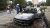 Taliban fighters investigate a damaged car after several rockets were fired at Kabul's airport on August 30. 