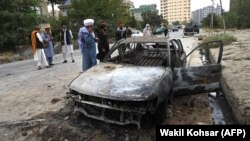 Taliban fighters investigate a damaged car after several rockets were fired at Kabul's airport on August 30. 