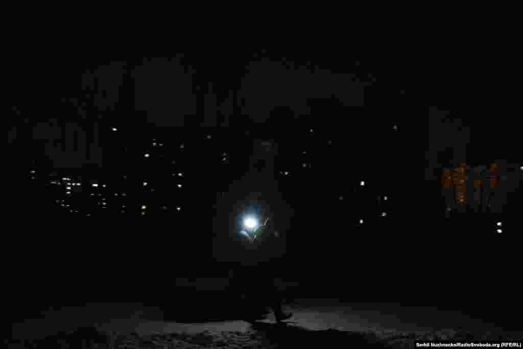 Люди йдуть з увімкненим ліхтарем в Деснянському районі Києва