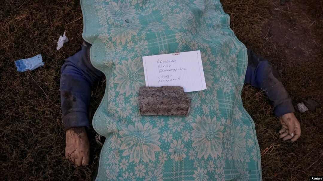 Cadavrul unei femei ucise, cu un bilet cu numele ei sub o piatră, în satul Hroza din regiunea ucraineană Harkov, 5 octombrie 2023.