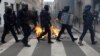 Francuska interventna policija prolazi pored zapaljenih kanti za smeće usred sukoba sa demonstrantima u sklopu devetog dana štrajkova širom zemlje i protesta protiv penzione reforme francuske vlade, u Parizu, 23. marta 2023.