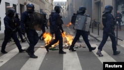 Francuska interventna policija prolazi pored zapaljenih kanti za smeće usred sukoba sa demonstrantima u sklopu devetog dana štrajkova širom zemlje i protesta protiv penzione reforme francuske vlade, u Parizu, 23. marta 2023.