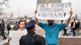 RUSSIA -- A Russian police officer speaks with an opposition supporter holding a poster reading "No war, repressions and tortures!" during a rally in support of jailed Kremlin critic Aleksei Navalny in Vladivostok, April 21, 2021