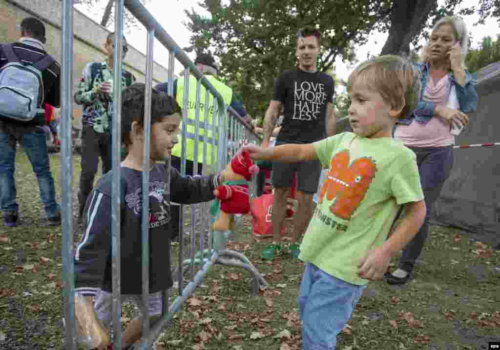 A migrant child receives a stuffed toy animal from a local toddler as a group of migrants arrives at the Slovenian-Austrian border station in Bad Radkersburg, Austria. (epa/Erwin Scheriau)