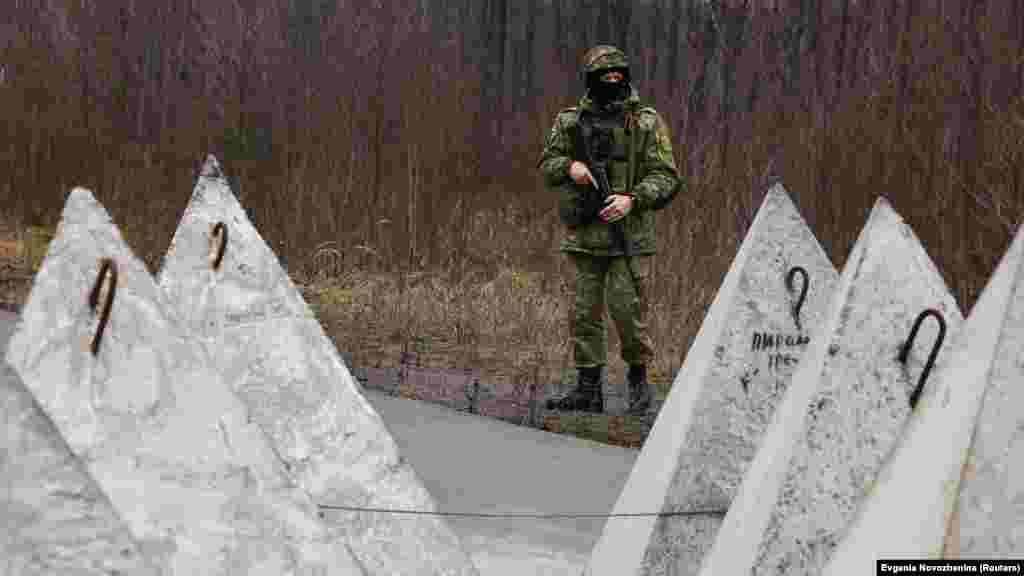 Беларускі вайсковец патрулюе мяжу з Украінай. На фота відаць супрацьтанкавыя ўмацаваньні, так званыя &laquo;зубы цмока&raquo;