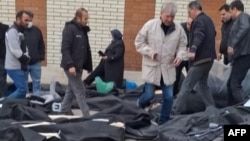 Родственники ищут своих близких среди десятков тел, лежащих на земле возле морга, Иран, 13 января 2026 года