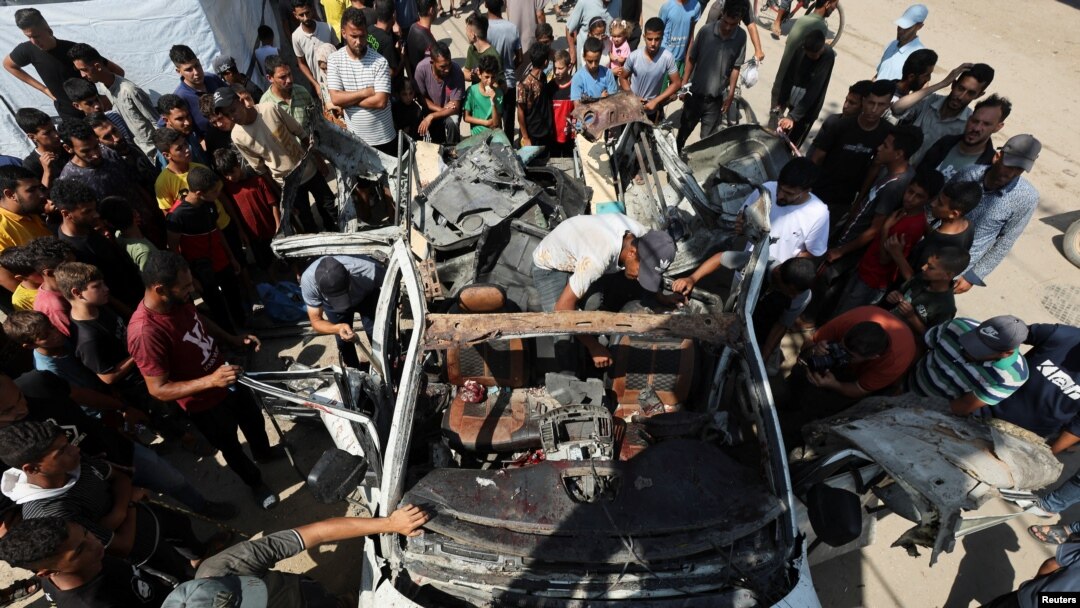 Palestinienii se adună lângă un vehicul distrus de un atac israelian în Deir Al-Balah, în centrul Fâșiei Gaza. 4 iunie 2024. 