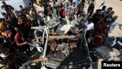 Palestinienii se adună lângă un vehicul distrus de un atac israelian în Deir Al-Balah, în centrul Fâșiei Gaza. 4 iunie 2024. 