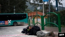 Сотрудники израильских сил безопасности укрываются во время воздушной тревоги в городе Кирьят-Шмона, заставшей их на месте падения ракеты группировки "Хезболла", выпущенной с территории Ливана. 23 марта 2026 года