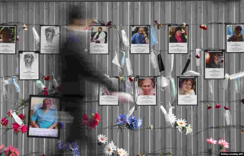 Medical face masks and portraits of medical workers who have died from the coronavirus during their work hang at a unofficial memorial in front of the local health department in St. Petersburg, Russia. (AP/Dmitry Lovetsky)