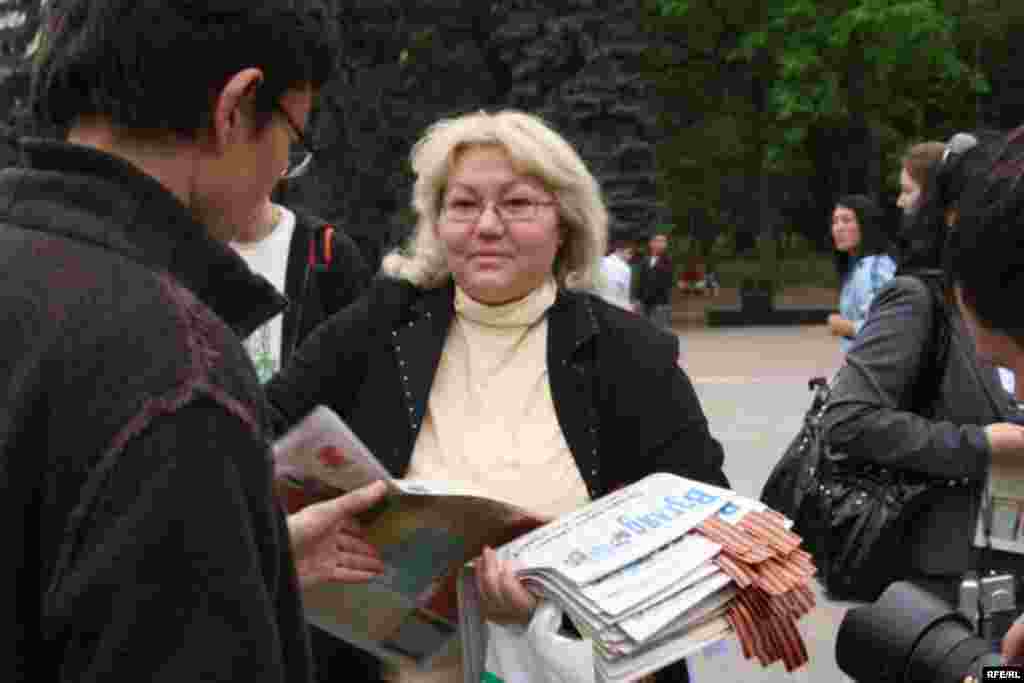 Активистка партии "Алга" раздает прохожим георгиевские ленточки и газеты. Алматы, 1 мая 2010 года.