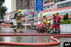 Zjarrfikësit duke pastruar një rrugë të vërshuar në Hong Kong më 8 shtator 2023.