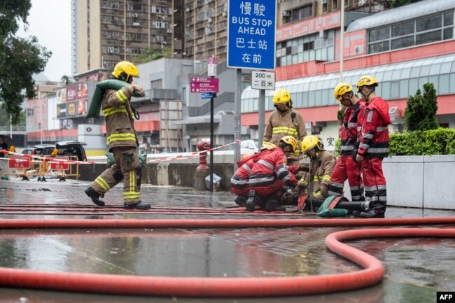 Zjarrfikësit duke pastruar një rrugë të vërshuar në Hong Kong më 8 shtator 2023.