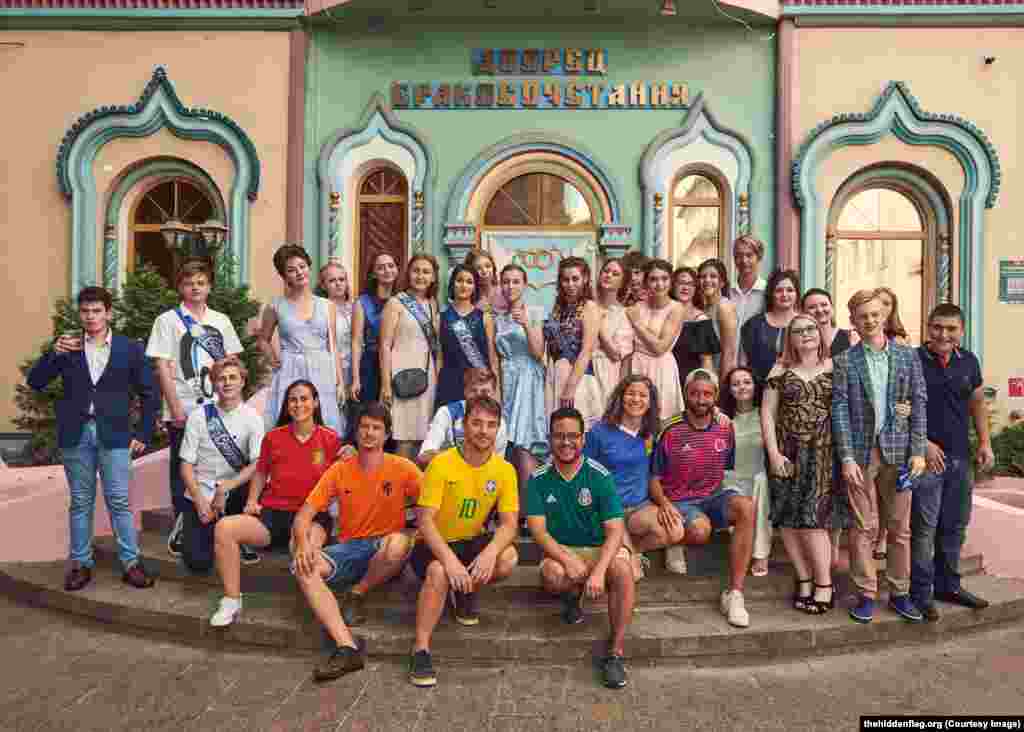 The group pose with a group of unwitting Russian high-school students on their graduation day. &nbsp;