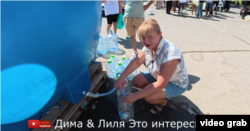 Блогерка Ліля набирает технічну воду зі стаціонарного бака, який поставила окупаційна влада Маріуполя. Ютуб-канал «Діма і Лиля Это интересно», 10 серпня 2026 року