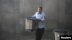 An Iraqi official carries a ballot box, after a fire at a storage site in Baghdad on June 10. 