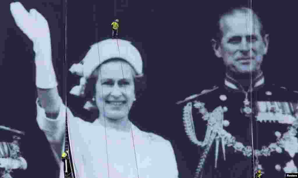 Abseilers along the River Thames&nbsp;secure a giant canvas with a photograph showing the Royal Family during Queen Elizabeth&#39;s Silver Jubilee celebrations in 1977. The queen is celebrating 60 years on the throne in 2012. (Reuters/Suzanne Plunkett)