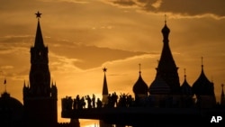 People watch and photograph a sunset behind the Kremlin at Zaryadye Park in Moscow. 