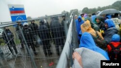 Zeci de migranți stau în ploaie în timp ce așteaptă să treacă granița dinspre Slovenia în Croația, 19 octombrie 2015.