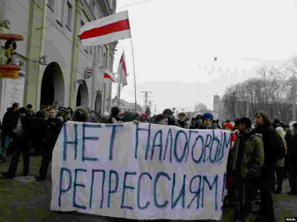 Удзельнікі акцыі рушаць па ходніках ў бок плошчы Незалежнасьці. Яны трымаюць расьцяжку "Не -- падатковым рэпрэсіям". 