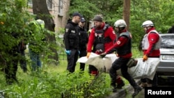 Ukrainian emergency workers carry the body of a resident who died when a Russian drone hit an apartment building in Kyiv on May 7.
