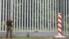 A Polish border guard patrols the area of a newly built metal wall on the border with Belarus, near Kuznice, Poland, in June 2022.