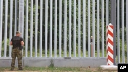 A Polish border guard patrols the area of a newly built metal wall on the border with Belarus, near Kuznice, Poland, in June 2022.