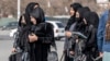 (FILES) Afghan female students studying health studies walk along a street in Kabul on December 3, 2024.