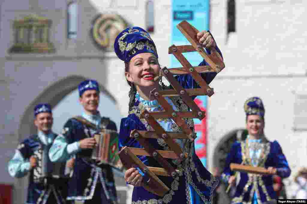 A performer dances with a traditional musical instrument.