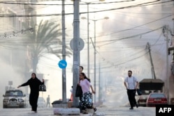 Палестинцы бегут в укрытие после удара возле больницы Аль-Шифа в городе Газа 1 ноября 2023 года на фоне продолжающихся боев между Израилем и палестинской группировкой ХАМАС.