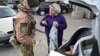 A Ukrainian border guard wearing a protective face mask searches a car and checks the passport of a woman leaving Ukraine and heading into territory controlled by Russia-backed separatists at the checkpoint near Novotroitske in the Donetsk region on March 16.