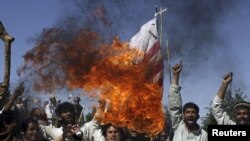 Afghan villagers burn a U.S. flag during a protest against NATO raids.