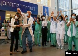 Медичні бригади святкують перед тим, як отримати вакцини проти коронавірусної хвороби (COVID-19), коли Ізраїль запускає акцію щеплення від коронавірусу в Тель-Авівському медичному центрі Сураскі (лікарня Ічілова) в Тель-Авіві, Ізраїль, 20 грудня 2020 року